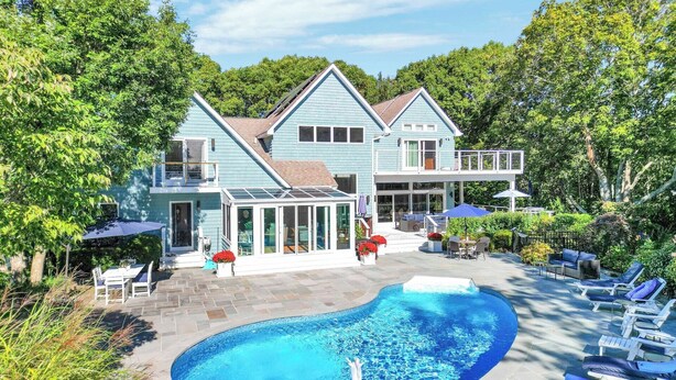 Ein großes Haus mit Swimmingpool, Sitzgelegenheiten im Freien und einer überdachten Terrasse.