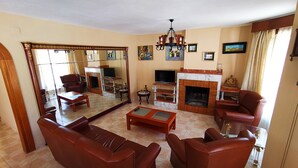 Una sala de estar con chimenea, sofás de cuero, un televisor y un espejo grande.