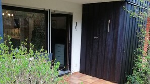A modern building with a dark exterior, a tiled patio area, and a sliding glass door leading to an interior space. - Mike's apartment incl. Oberstaufen Plus Card (Steibis)