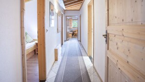 A hallway with wooden beams, a bed, a dining area, and a door. - Ferienhof Sonnseitn by Interhome (Kaltenbach)