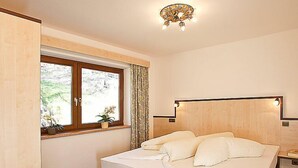 A bedroom with a bed, a window with curtains, a bedside table, and a nightstand. - Apartment Alpin by Interhome (Sölden)