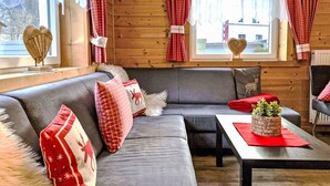 Ett mysigt rum med en grå soffa, rött och vitt rutiga gardiner och en hjärtformad dekoration på fönsterbrädan.