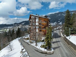 A multi-story building with balconies, a snow-covered landscape, and a mountainous backdrop. - Le Bristol A46 by Interhome (Villars)