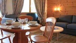 Una stanza accogliente con arredamento in legno, un tavolo da pranzo apparecchiato con ciotole e bicchieri, un divano e un piccolo tavolo rotondo con una sedia.