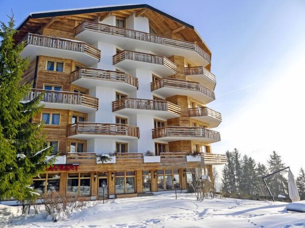 A multi-story hotel with wooden balconies and a restaurant at the ground level. - Le Bristol A46 by Interhome (Villars)