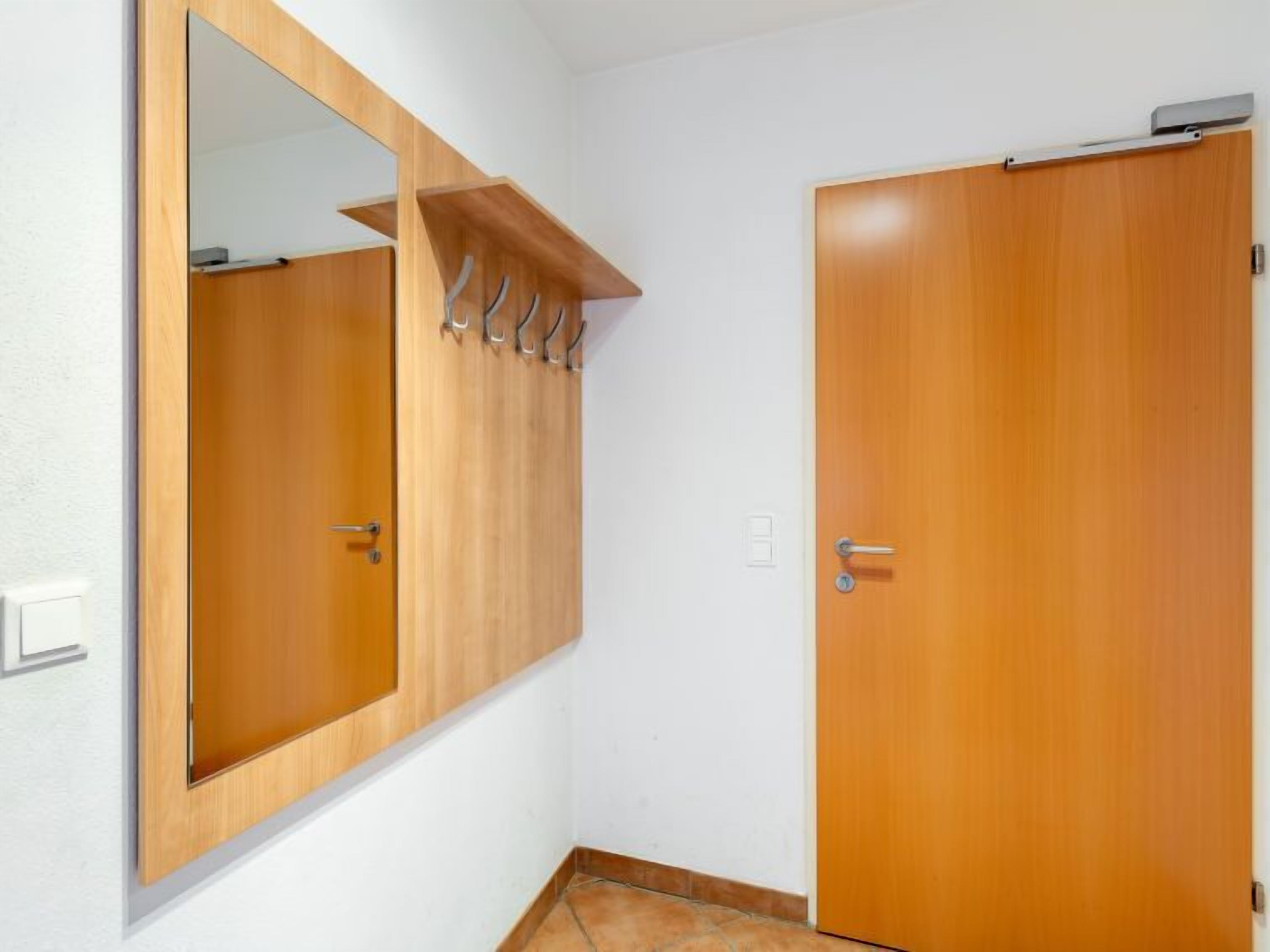 Una habitación con un armario de madera, un espejo y una puerta.