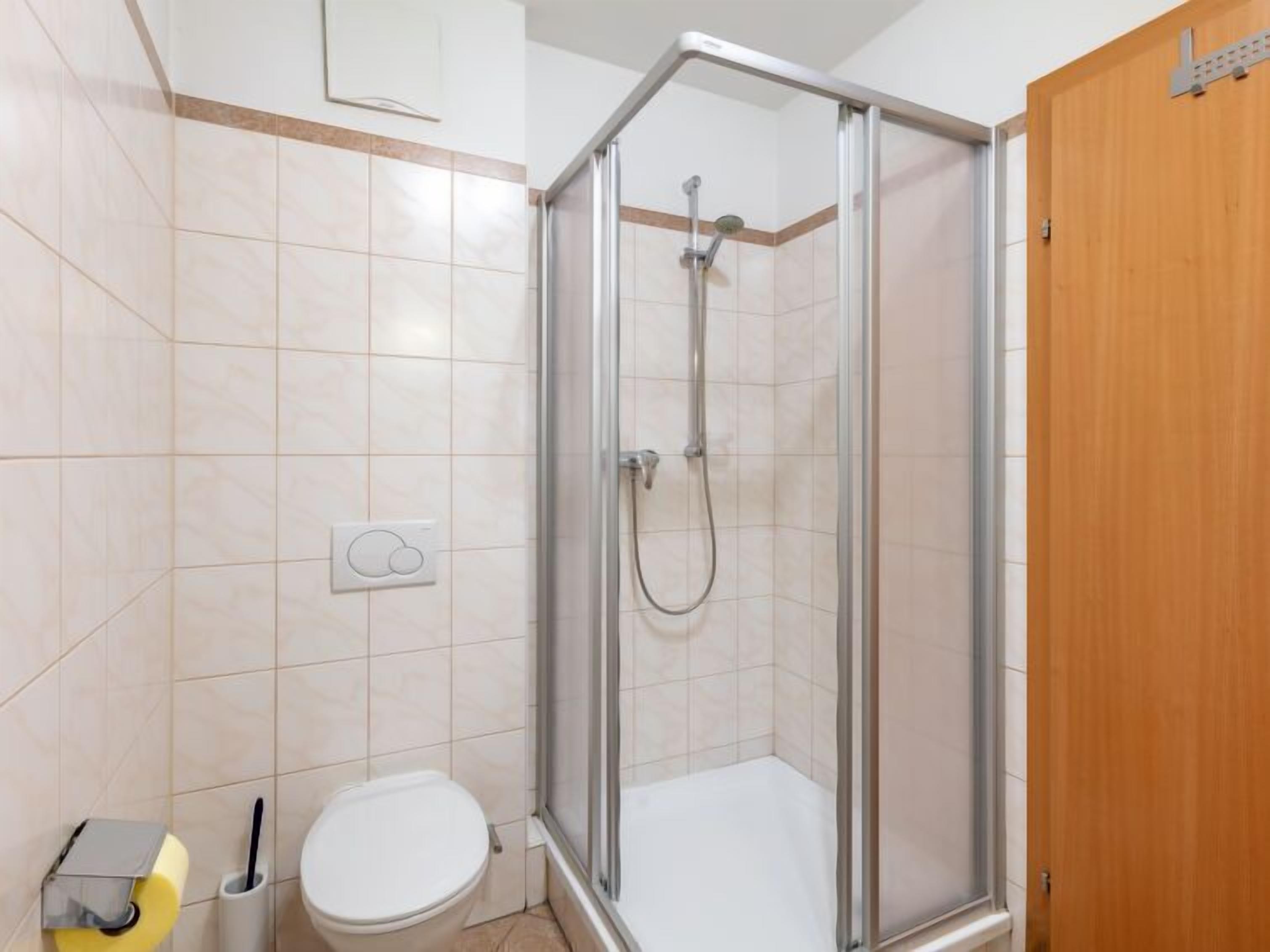 A small, modern bathroom with a shower, toilet, and a towel rack.