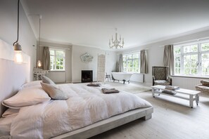 A spacious bedroom with a large bed, a classic clawfoot bathtub, and a chandelier. - Westerly House on Bantry Bay, West Cork (Ballylickey)