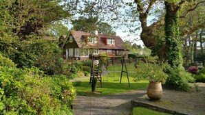 Ein traditionelles Haus mit einem gepflegten Garten, inklusive Schaukel und einem großen Blumenkasten.