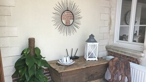 Un cofre de madera rústico con un farol blanco y un espejo decorativo sobre un suelo de baldosas.