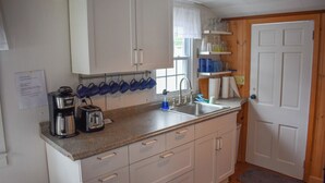 A compact kitchen with white cabinets, a coffee maker, a toaster, and a sink.