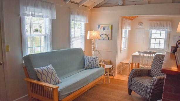 A cozy living room with a wooden sofa, a patterned armchair, and a small table with a lamp.