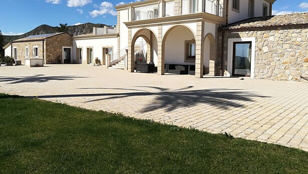 Un edificio grande de varios pisos con un patio central, muros de piedra y arcos.