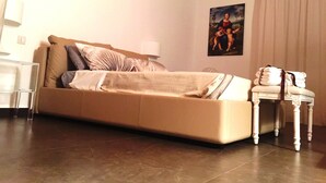 Un dormitorio con una cama, una silla, un cuadro y una lámpara.