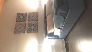 Una habitación con una cama, un banco y cuatro azulejos decorativos en la pared.