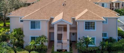A two-story residential building with a central entrance, a balcony, and a driveway.