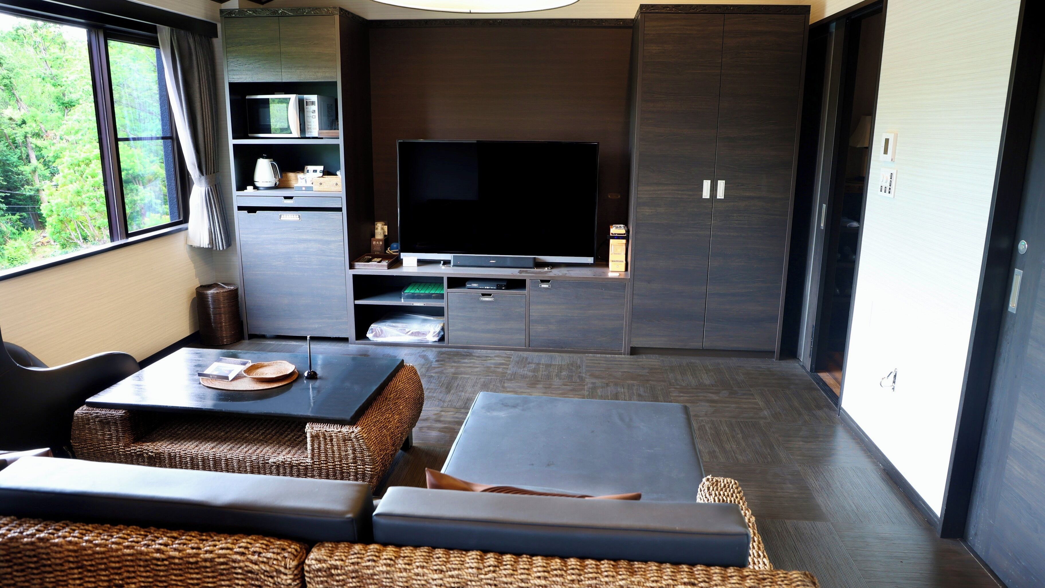 Una sala de estar moderna con un televisor de pantalla plana, armarios empotrados y una zona de estar con una mesa.
