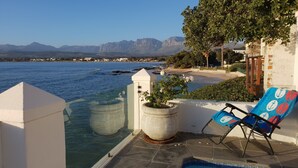 A poolside area with a clear view of the sea and mountains in the background. - Westbank (Cape Town)
