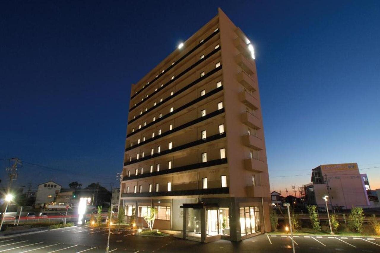 A multi-story hotel with a modern design, featuring a central courtyard and a parking area.