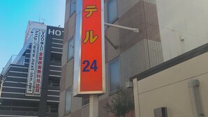 Un immeuble sur lequel est apposée une enseigne verticale indiquant un hôtel nommé « Tatsumi Hotel », avec le numéro 24.