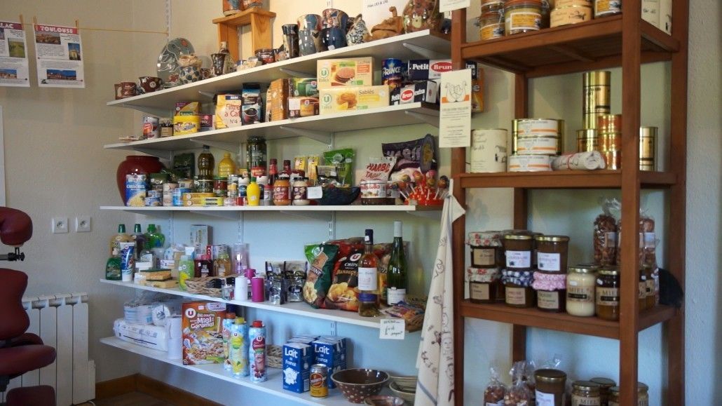 A room with shelves stocked with various food items, including jars, boxes, and bottles.