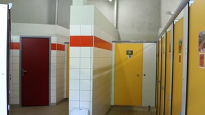 Un pasillo con casilleros, una puerta roja y un contenedor de basura.