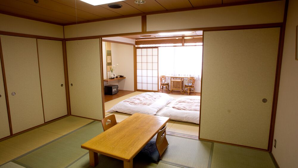 A traditional Japanese room with tatami flooring, a low wooden table, and sliding doors.