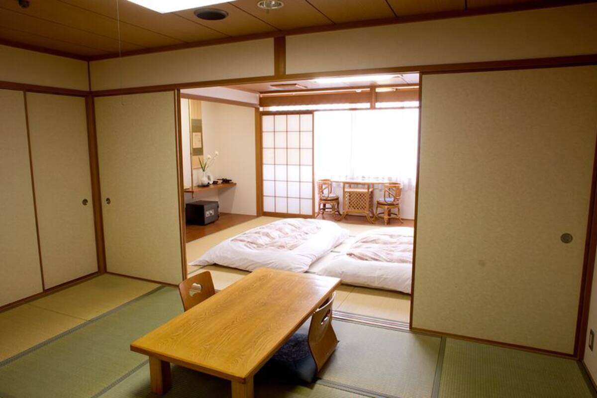 Une pièce de style japonais traditionnel, avec un sol recouvert de tatamis, une basse table en bois et des portes coulissantes.