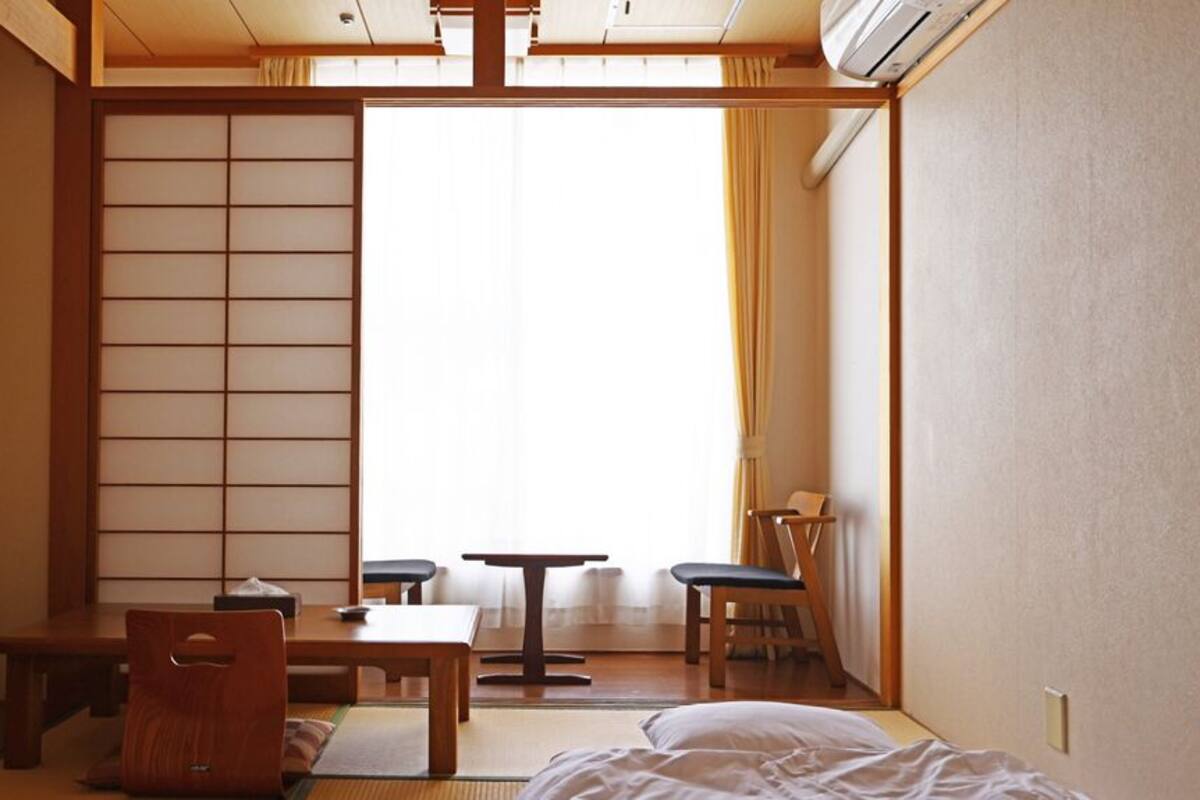 Une pièce de style japonais traditionnel, avec un sol recouvert de tatamis, une table basse, une chaise et un lit.