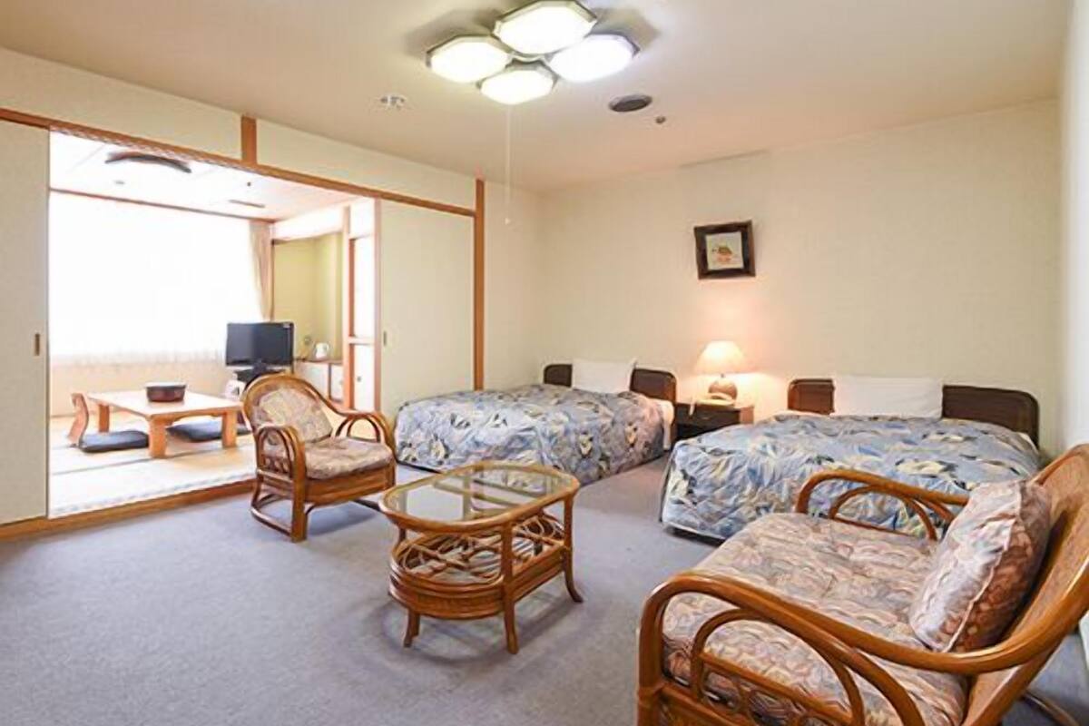 Une chambre avec deux lits, un canapé, une chaise, une petite table et un téléviseur.