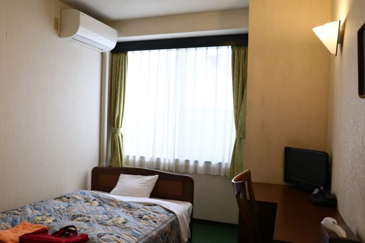 Une chambre d’hôtel équipée d’un lit, d’un bureau, d’une chaise, d’une télévision et d’un appareil de climatisation.