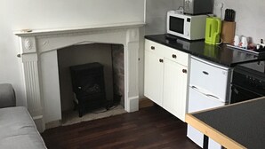A compact kitchen with a white fireplace, a microwave, and a toaster on the counter. - Number 16 at The Hub (Swansea)
