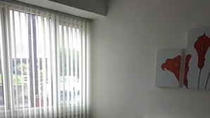 A living room with a grey sofa, a fireplace, and a window with blinds. - Number 16 at The Hub (Swansea)