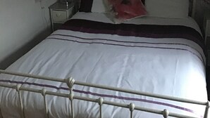 A bed with a white headboard and a floral-patterned wallpaper. - Number 16 at The Hub (Swansea)