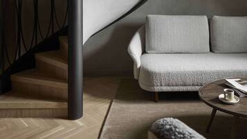 A modern interior with a curved staircase, a grey sofa, and a round coffee table.