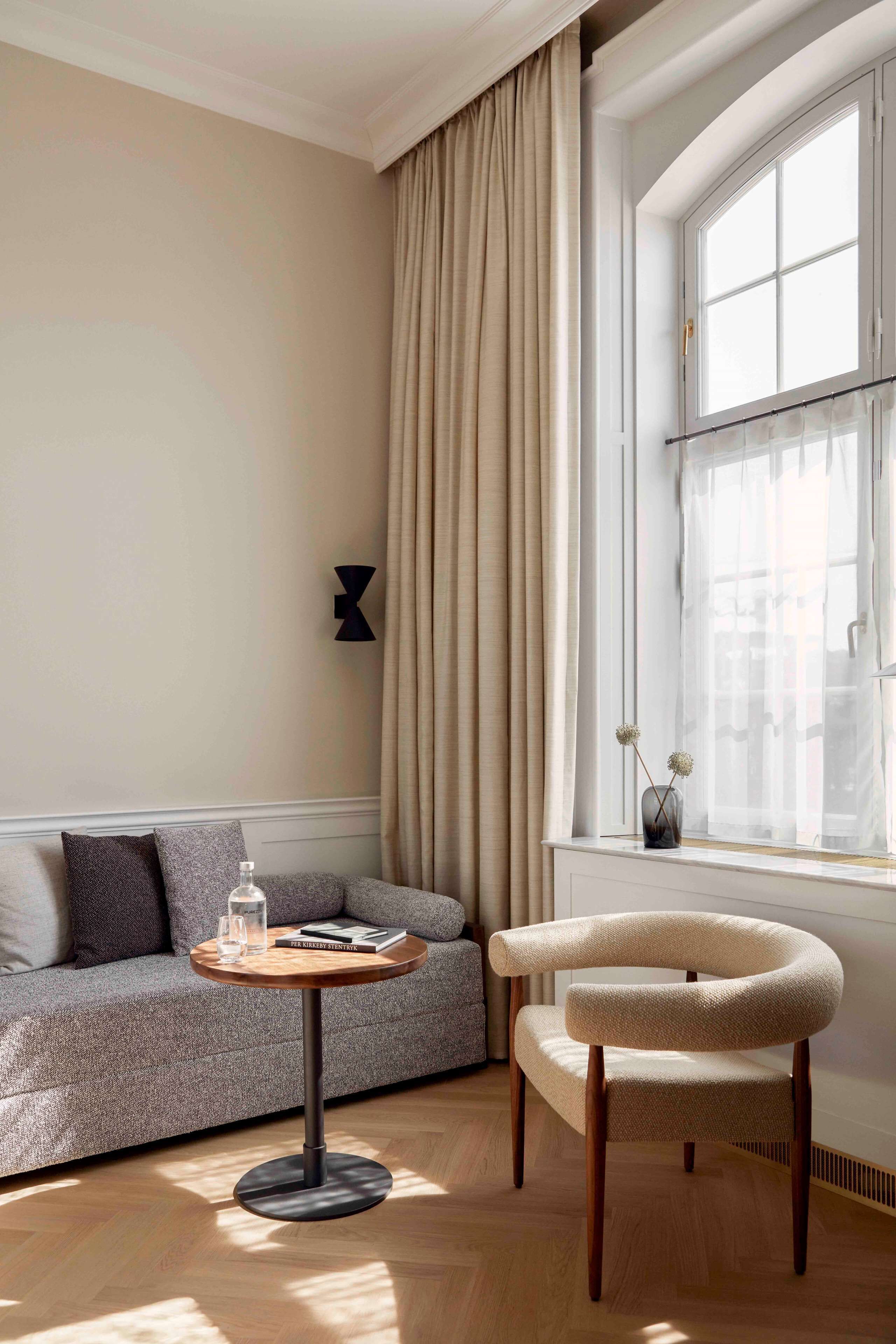 A modern living room with a sofa, a round wooden table, and a chair.