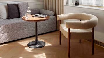 A modern living room with a sofa, a round wooden table, and a chair.