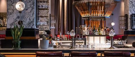 A bar area with marble walls, wooden bar counter, and stools.