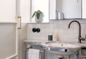 A modern bathroom with a white sink, a mirror, and a potted plant.