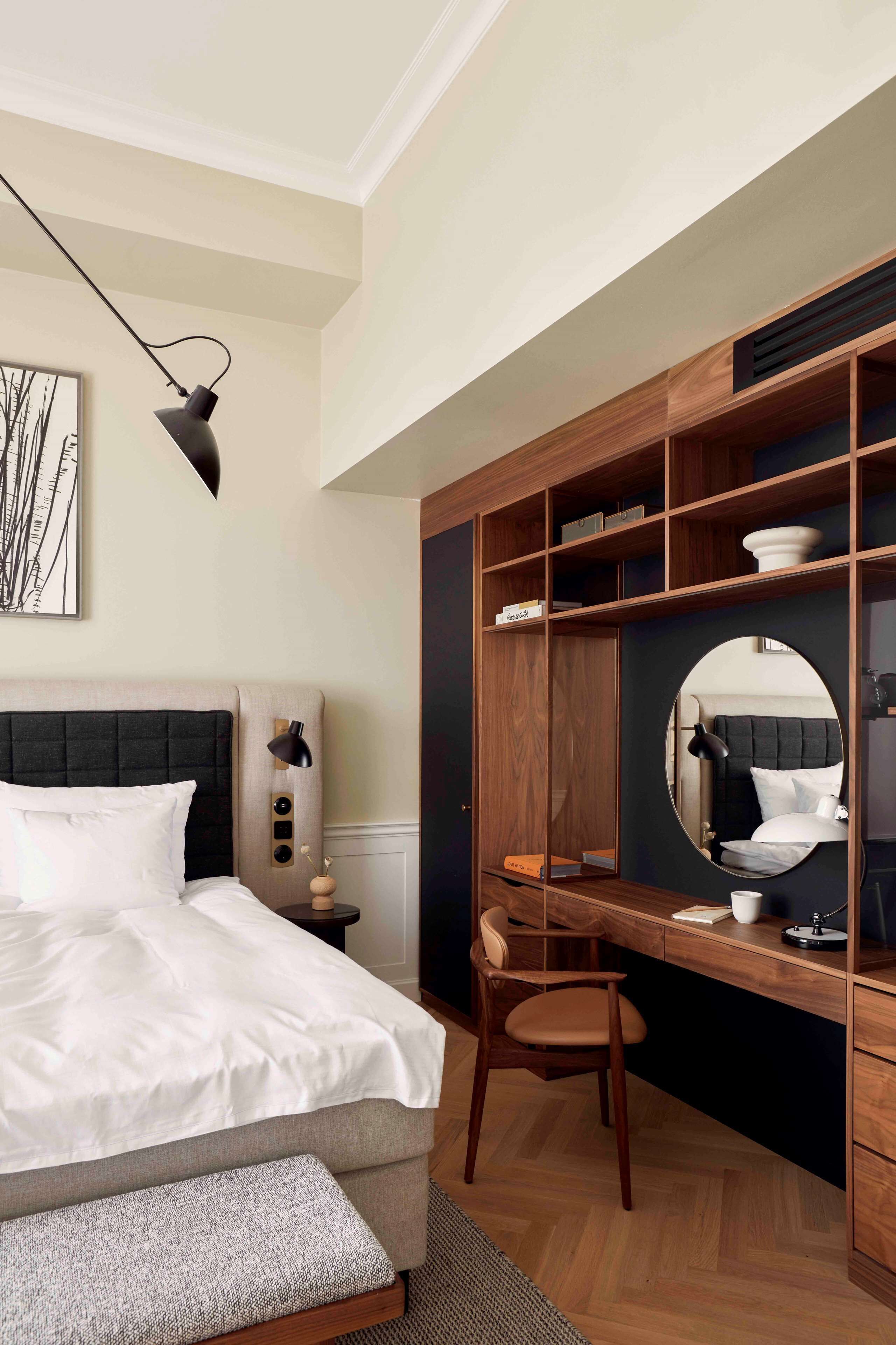 Un dormitorio con cama, mesita de noche, silla, escritorio y estanterías empotradas.