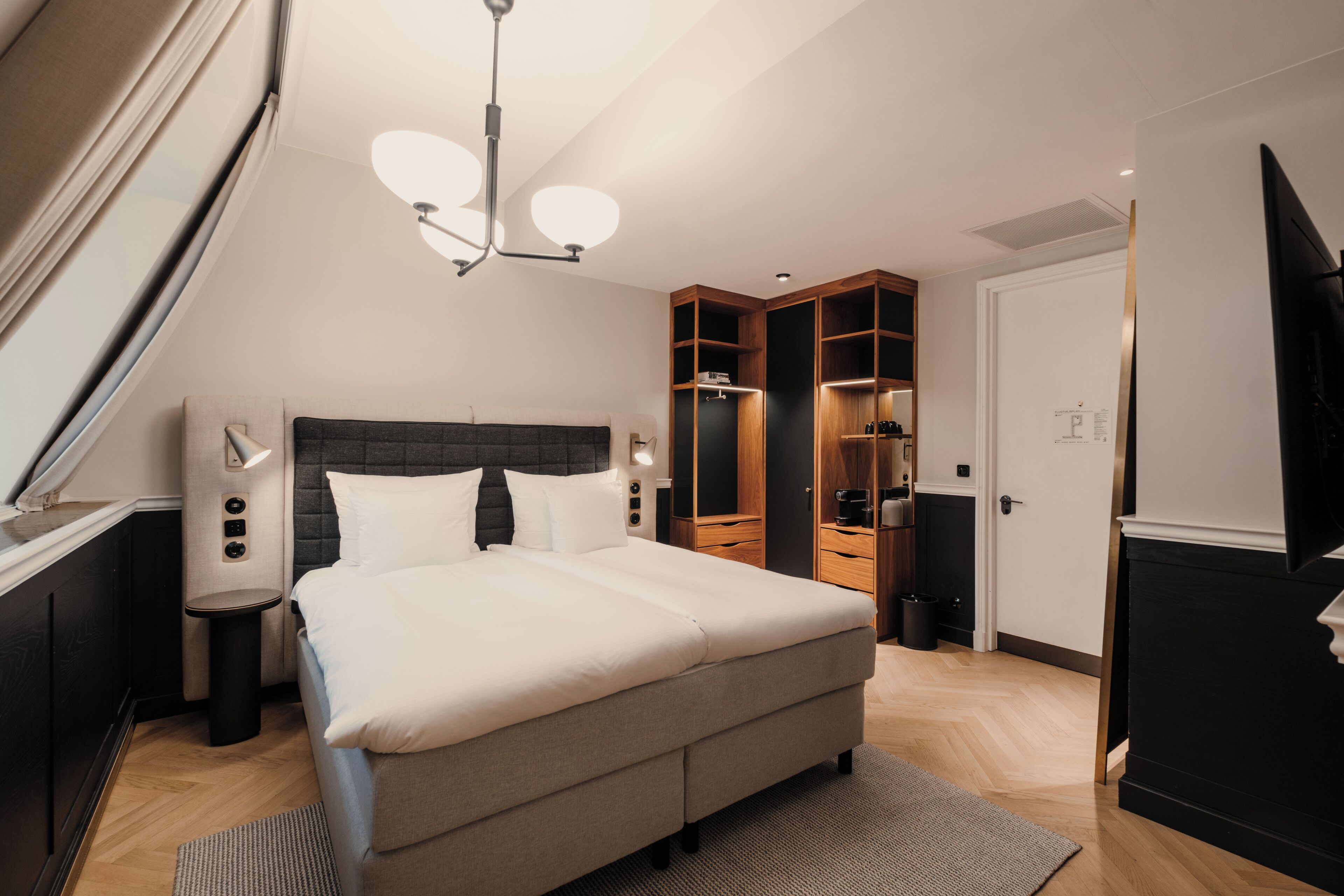 A modern bedroom with a large bed, built-in wardrobe, and a ceiling light fixture.