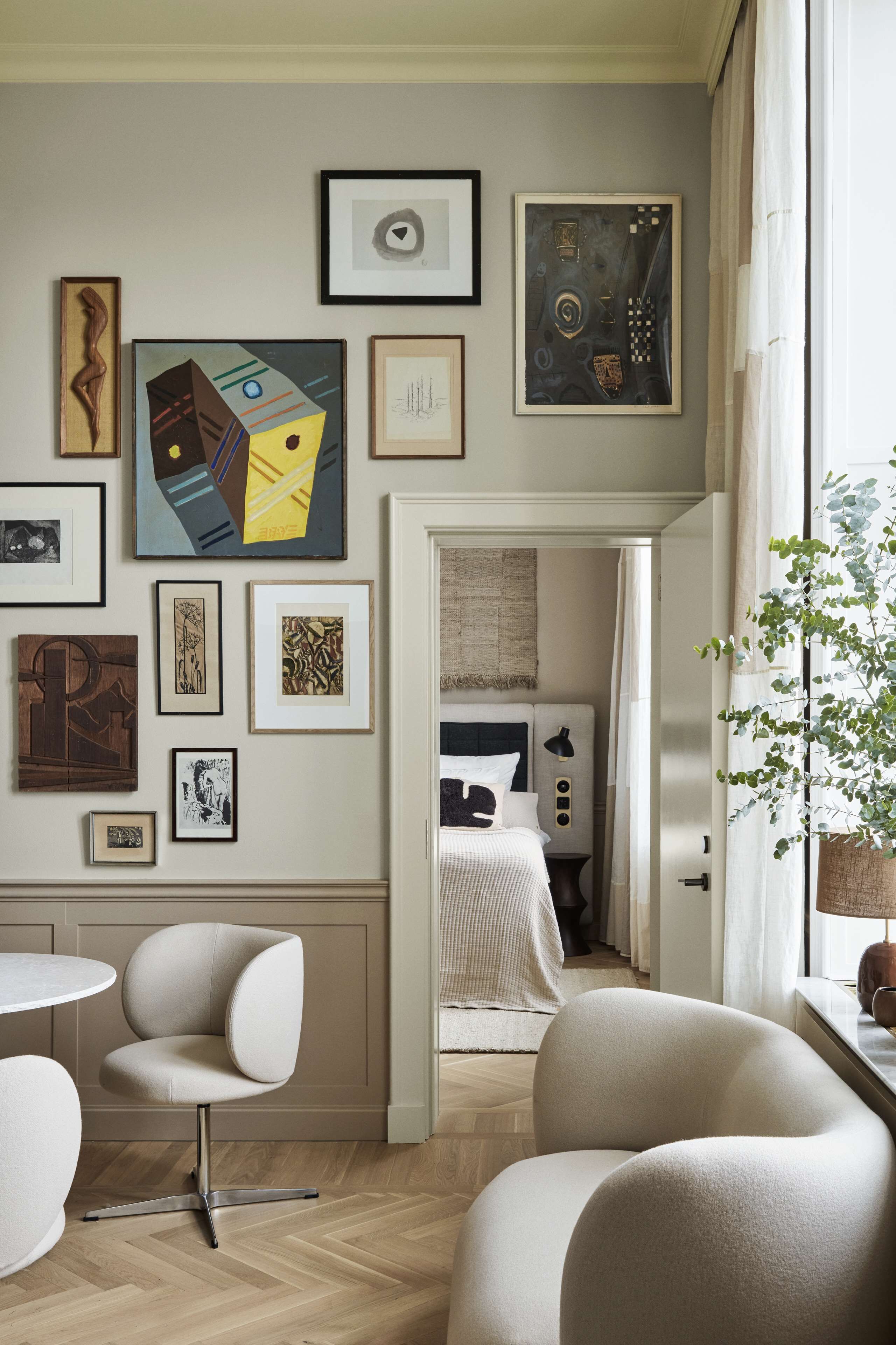 A modern hotel room with a minimalist design, featuring a large window, a comfortable seating area, and a variety of artwork on the walls.