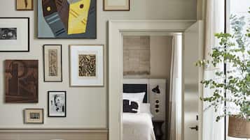 A modern hotel room with a minimalist design, featuring a large window, a comfortable seating area, and a variety of artwork on the walls.