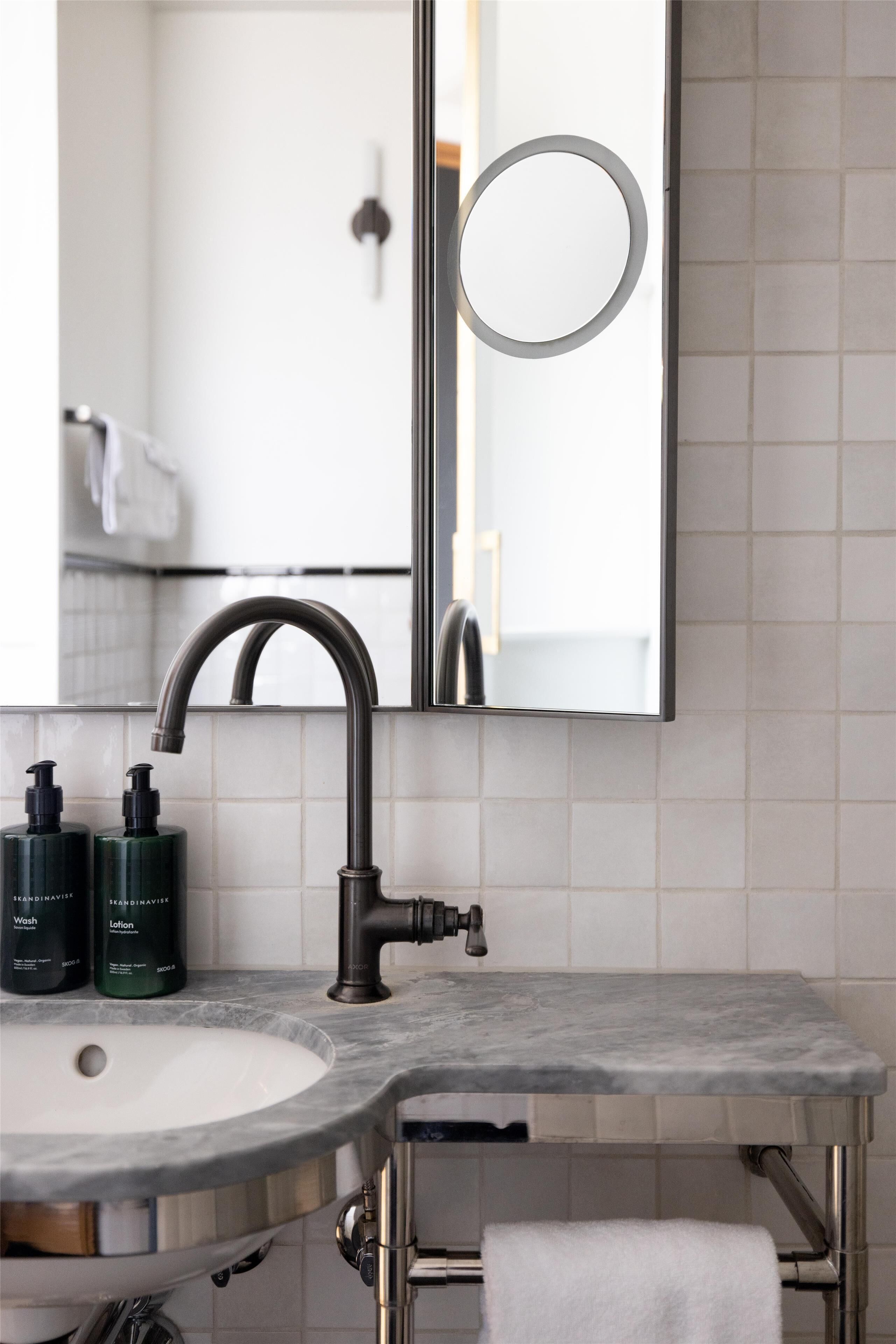 A bathroom with a sink, mirror, and two bottles of lotion.