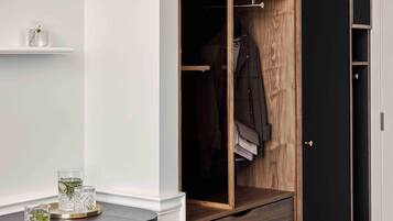 Un vestidor con estantes de madera, una planta en maceta y ropa colgada.