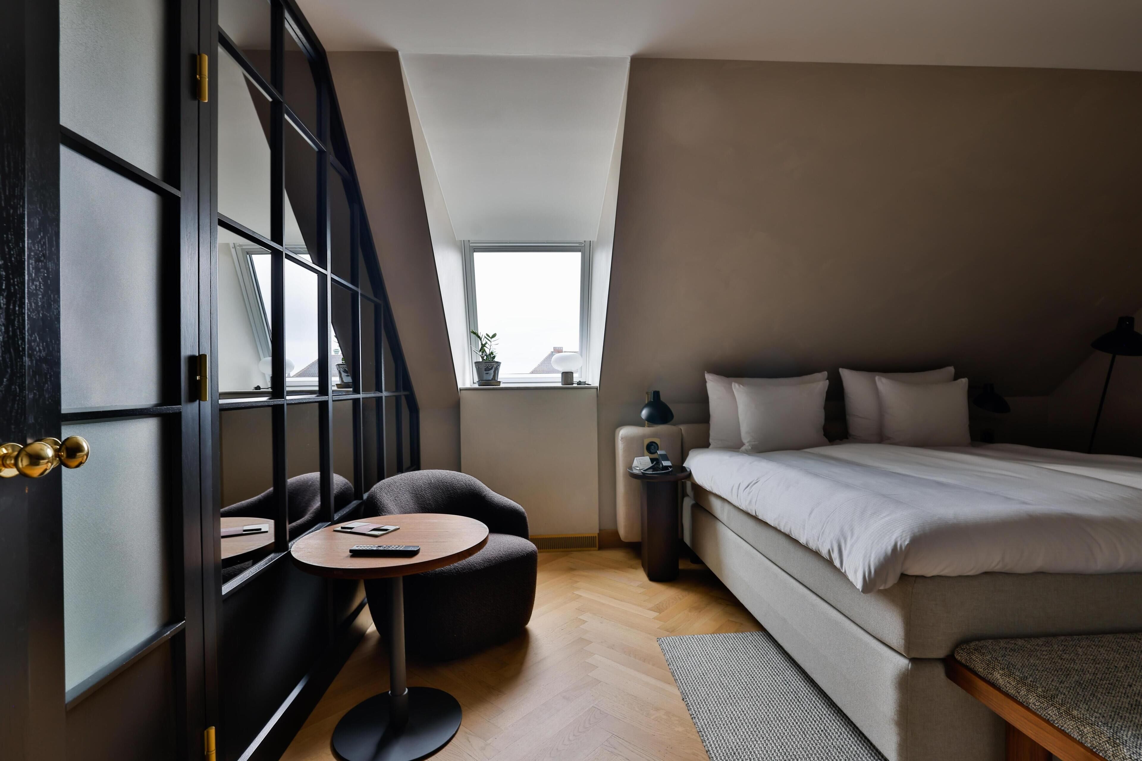 A modern bedroom with a bed, a desk, a chair, and a window.
