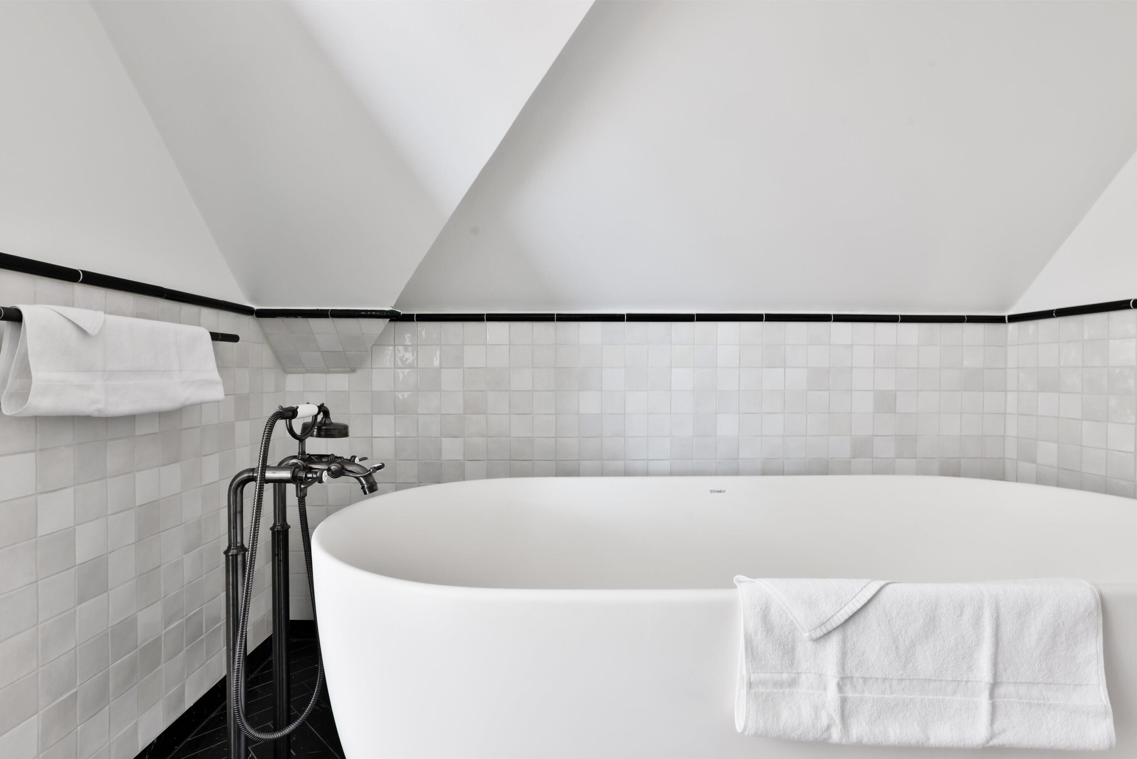 Un baño moderno con una bañera independiente, zona de ducha y un perchero para toallas.