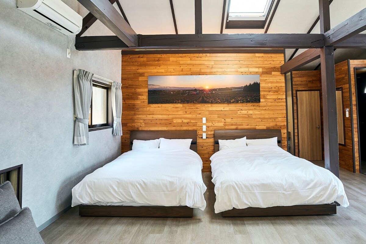 Een kamer met twee bedden, een houten wand en een groot raam.
