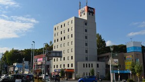 Um edifício de vários andares com um letreiro APA bem visível no topo, rodeado por diversos estabelecimentos comerciais.