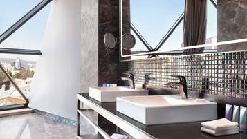 A modern bathroom with two sinks, a large mirror, and a view of the city.